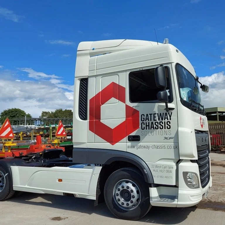 Side view of We Are Gateway white truck featuring a prominent red hexagonal logo.
